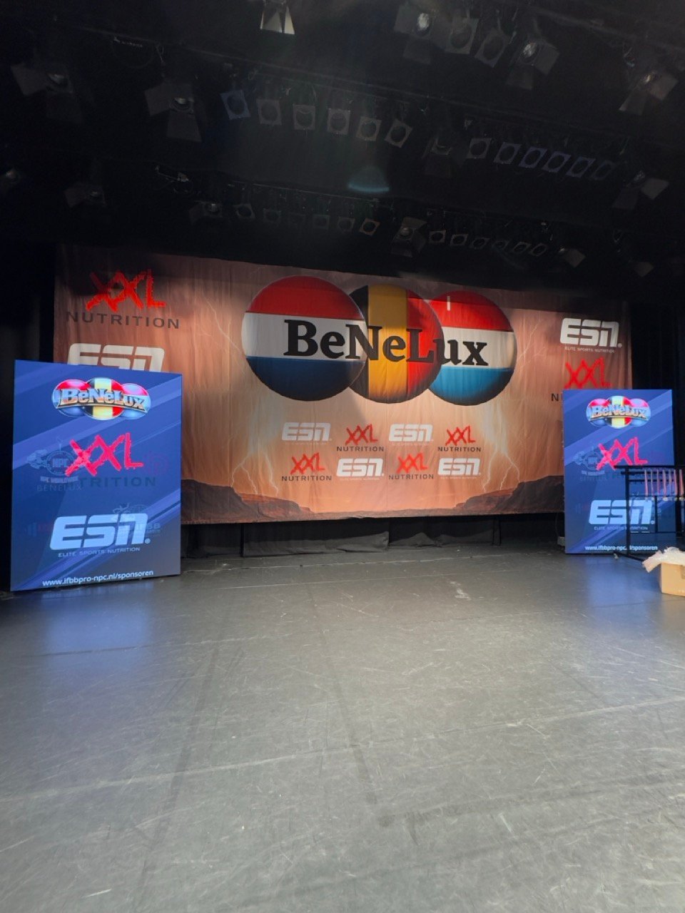 Stage setup with large Benelux logo banner, blue XXL signage on sides, and ESN branding for indoor event